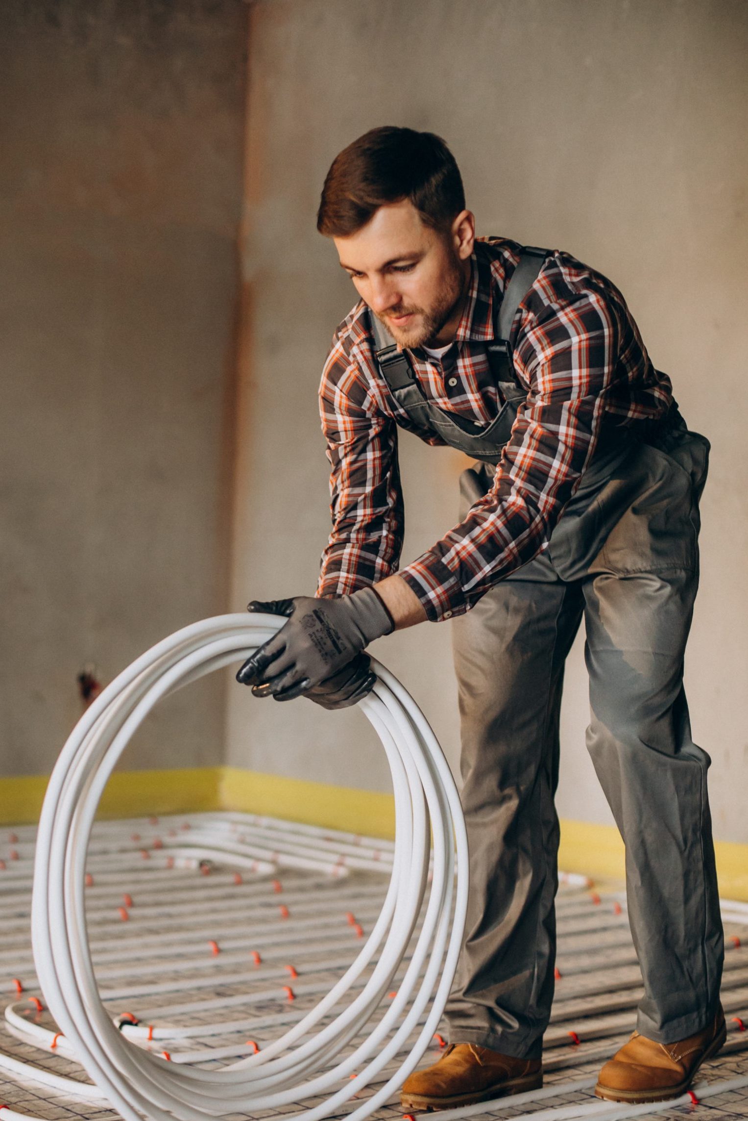 Service man instelling house heating system under the floor